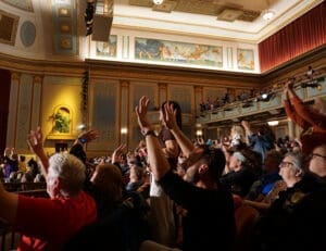 audience in a theatre with raised hands having fun at a show