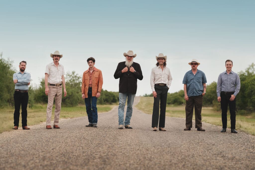 Asleep At The Wheel band members standing in a row on a dirt road