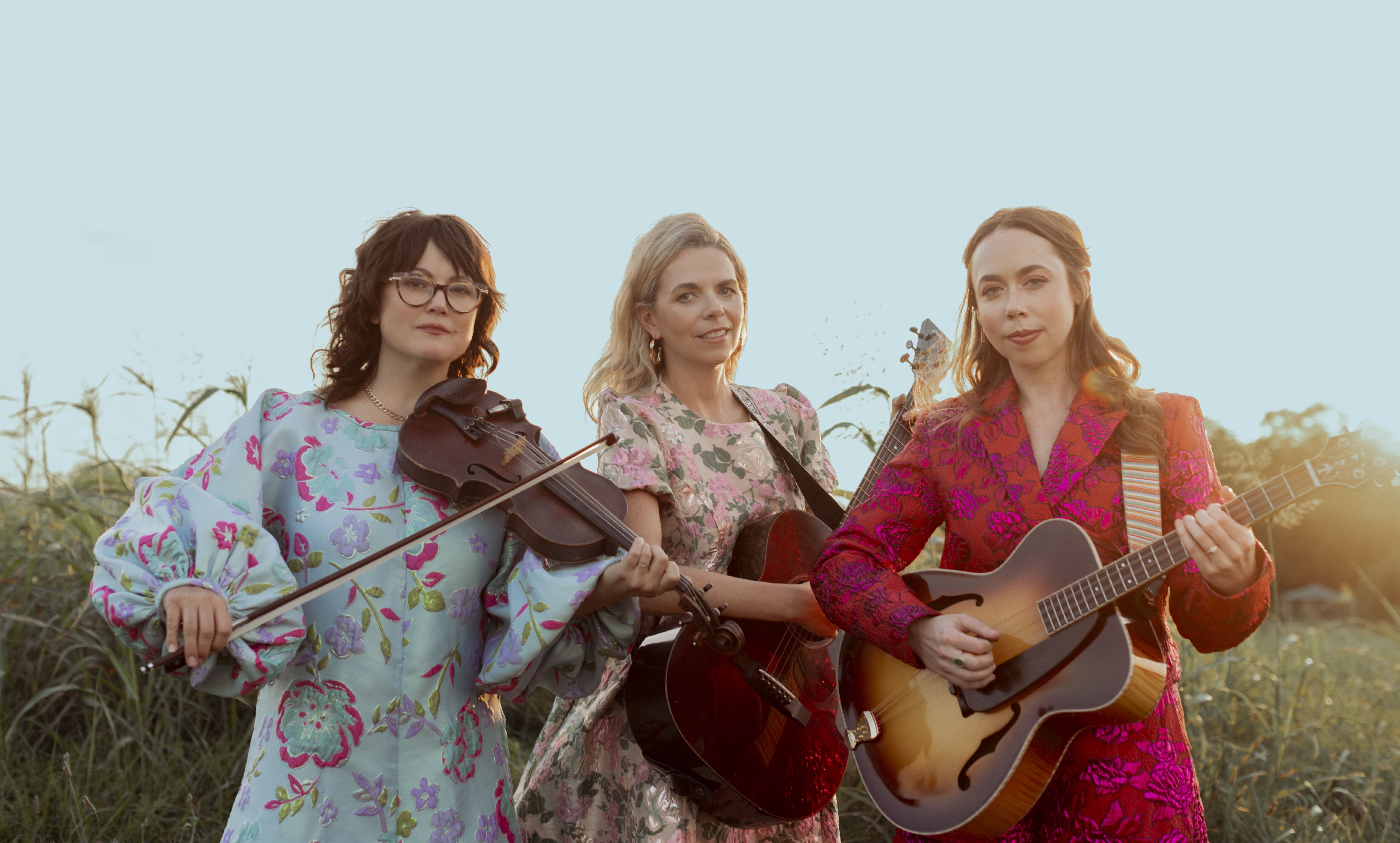 Sara Watkins, Aoife O'Donovan and Sarah Jarosz of I'm With Her standing outside holding instruments