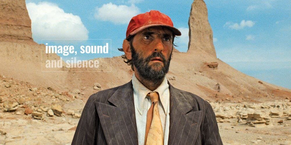 Harry Dean Stanton standing in a desert in Paris Texas