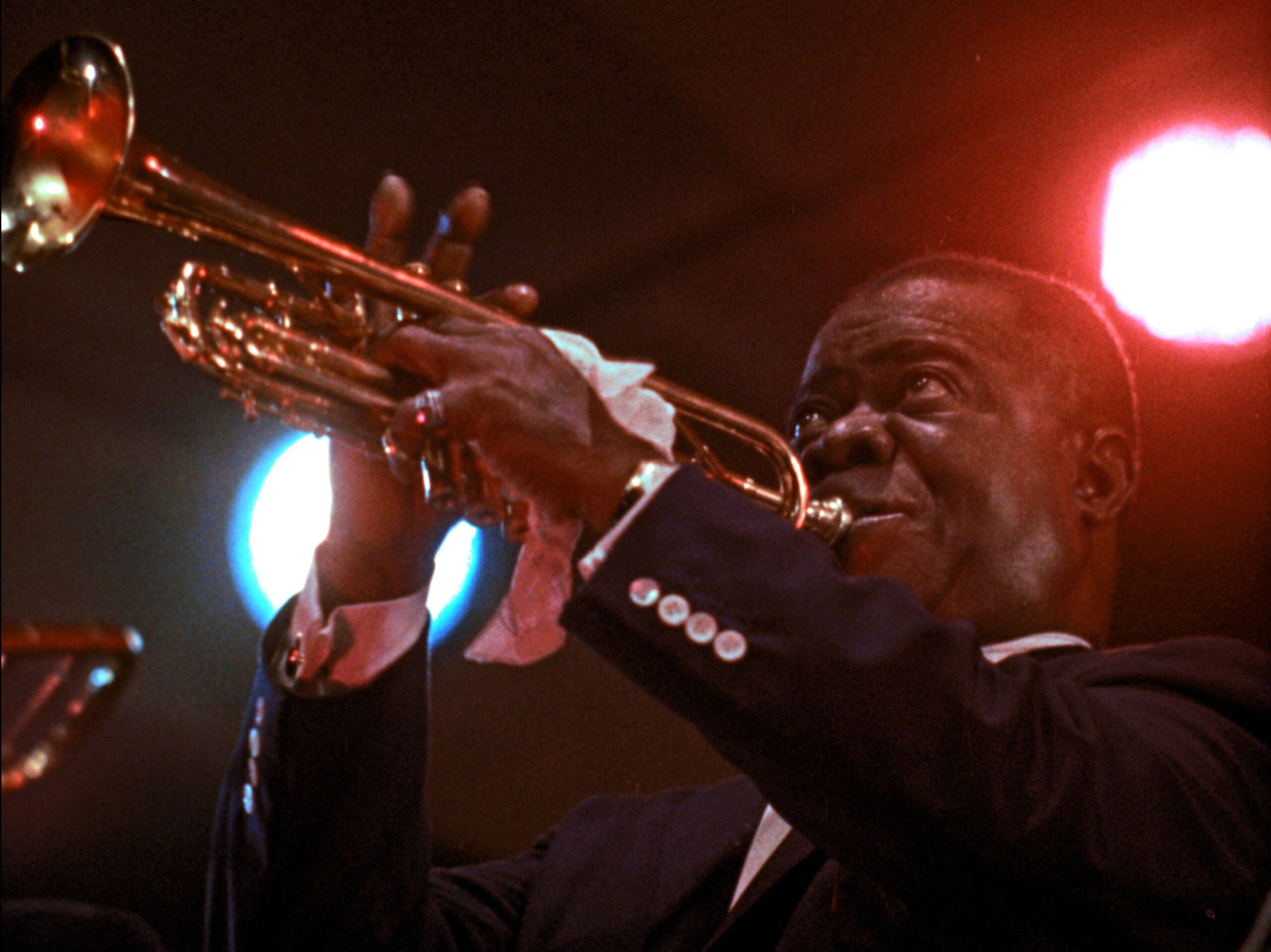 Louis Armstrong playing trumpt infront of a bright stage light