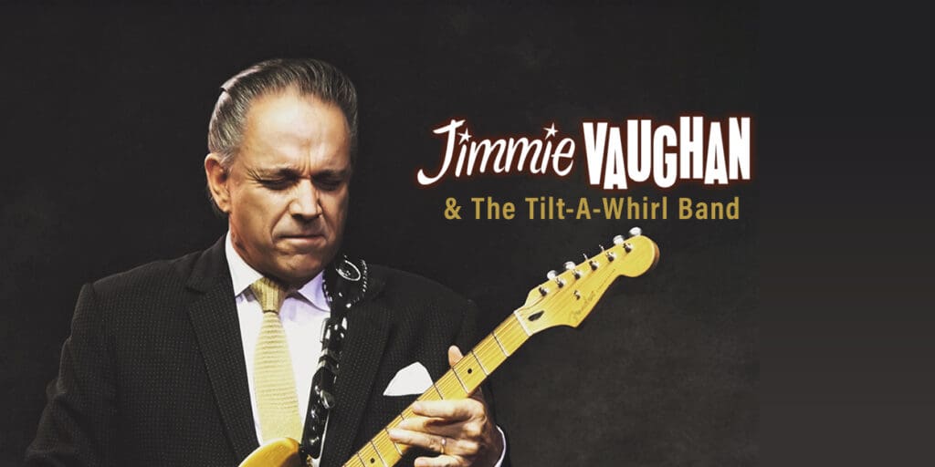 Jimmie Vaughan playing guitar against a black background