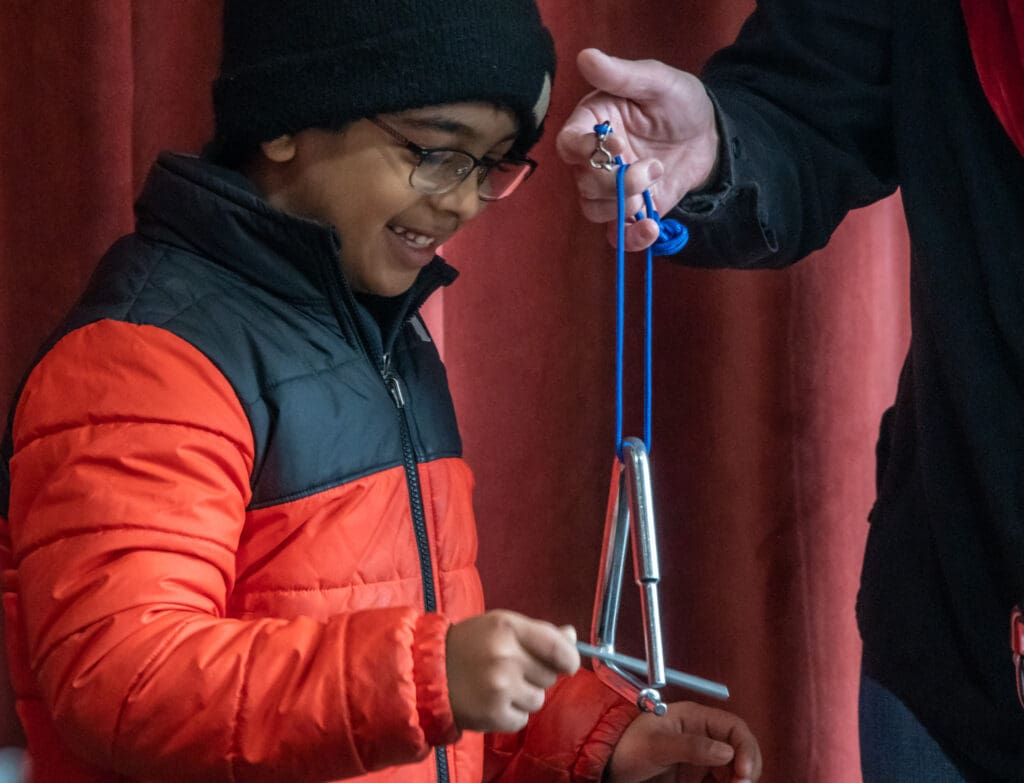 A young child plays a triangle