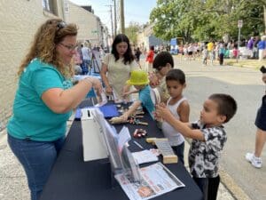 Appell Center staffer at a community event with children playing handheld instruments