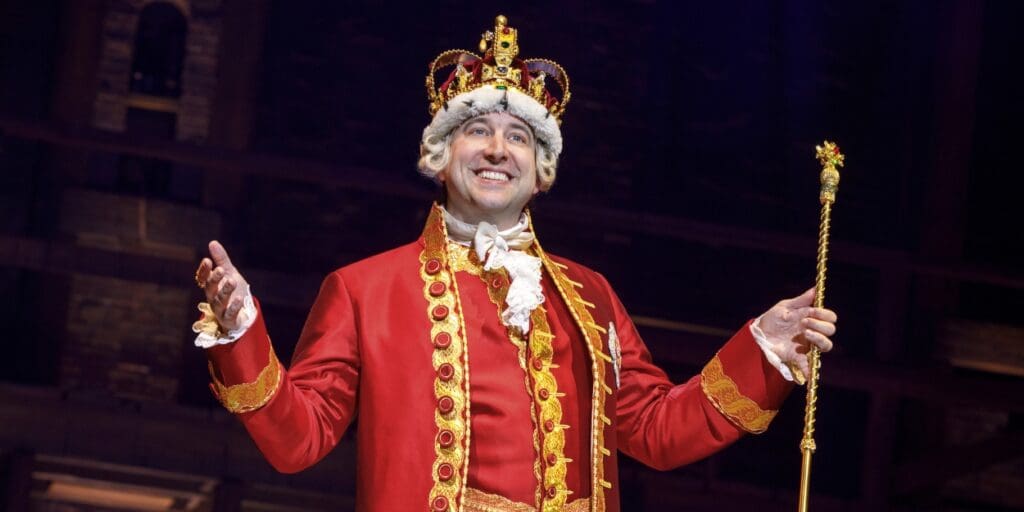 A man stands on stage dressed as King George