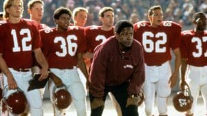 image from Remember the Titans with Denzel Washington crouching in front of members of his football team at a game