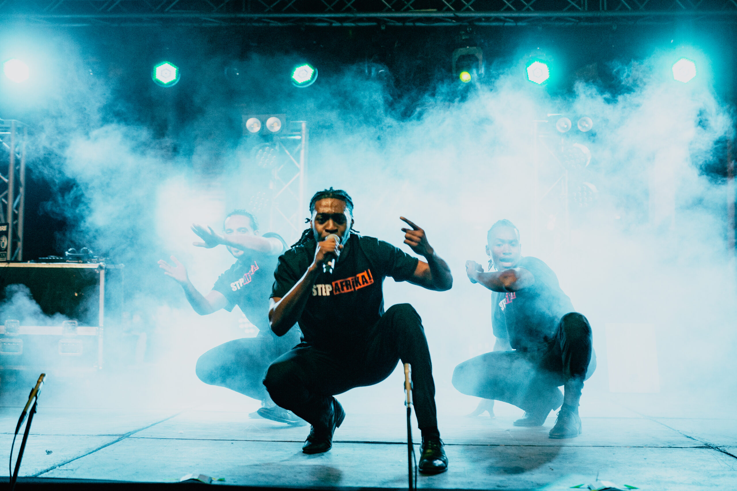 3 members of Step Afrika perfoming on stage surrounded by smoke and lighting effects