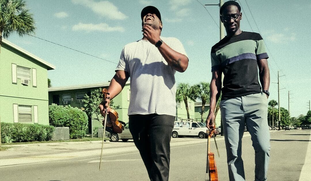 Black Violin CD cover photo of the guys walking down a street with their instruments