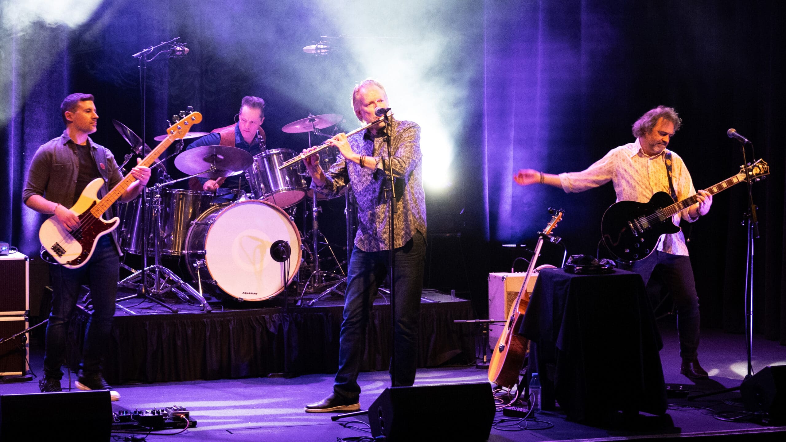 4 members of The Tull Project performing on stage wuth purple stage lights
