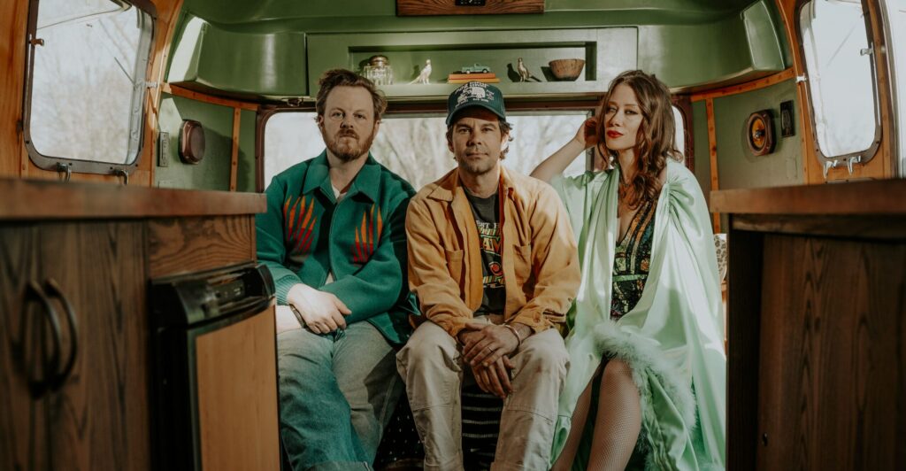 3 members of The Lone Bellow sitting in the back of an RV