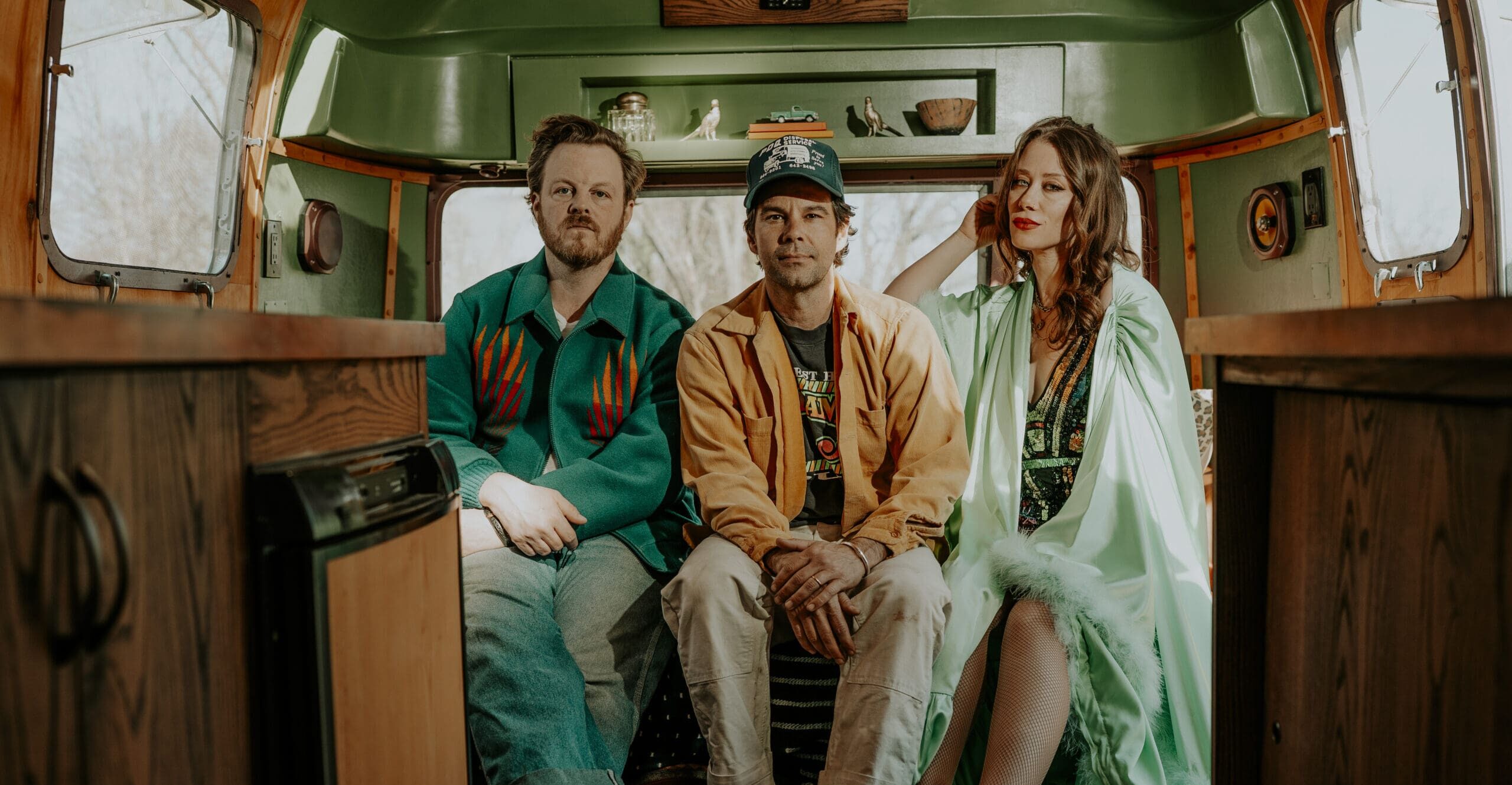 3 members of The Lone Bellow sitting in the back of an RV