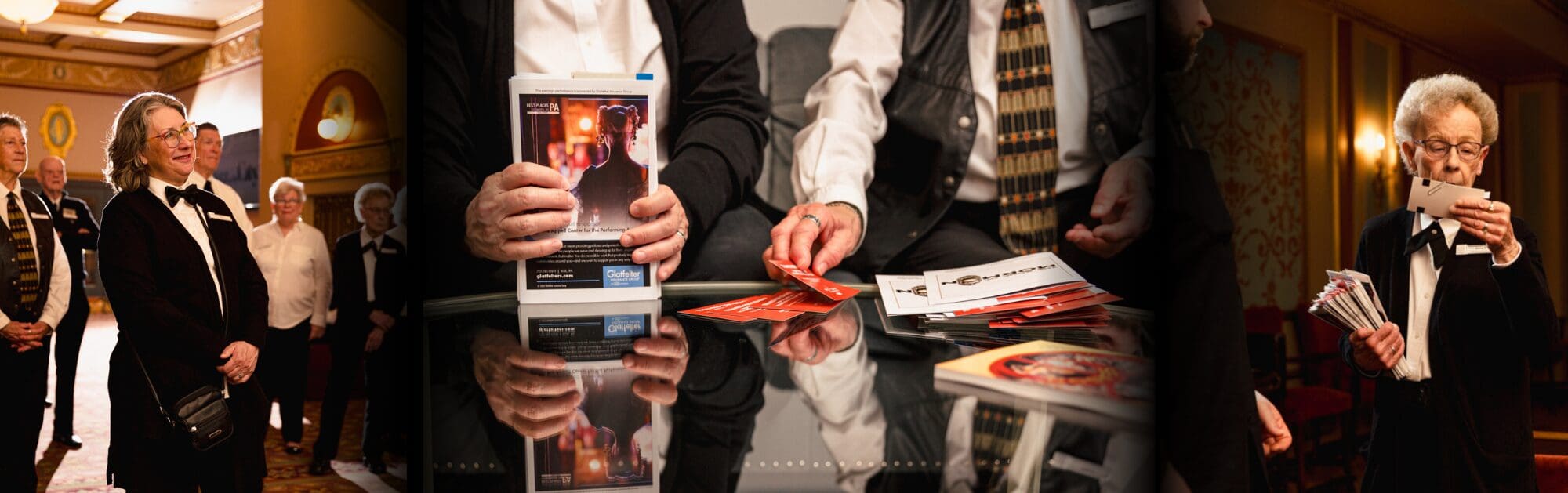 Group of ushers in formal attire stand and distribute tickets and programs inside a theater lobby with ornate decor.