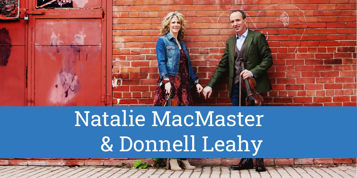 Natalie MacMaster and Donnell Leahy standing together against a red brick wall