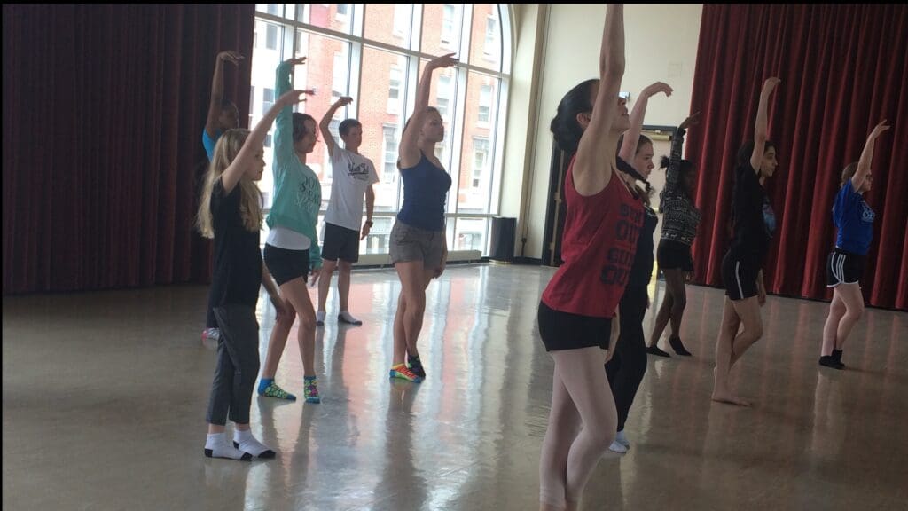 Dancers perform the same ballet move together in a dance studio