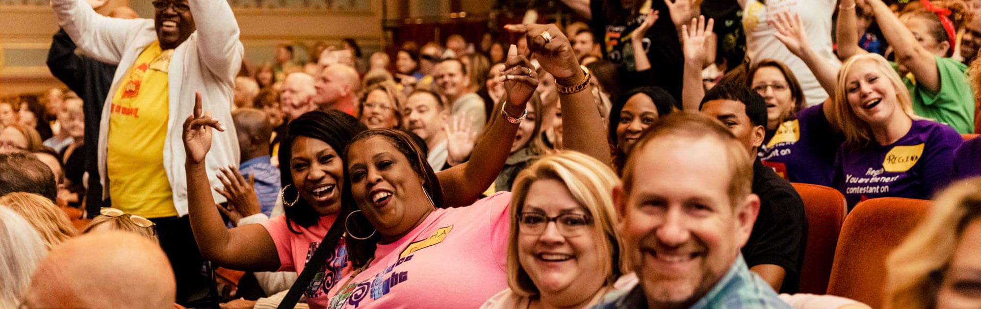 Guests attend The Price is Right in the Strand Theatre. They are smiling and waving.
