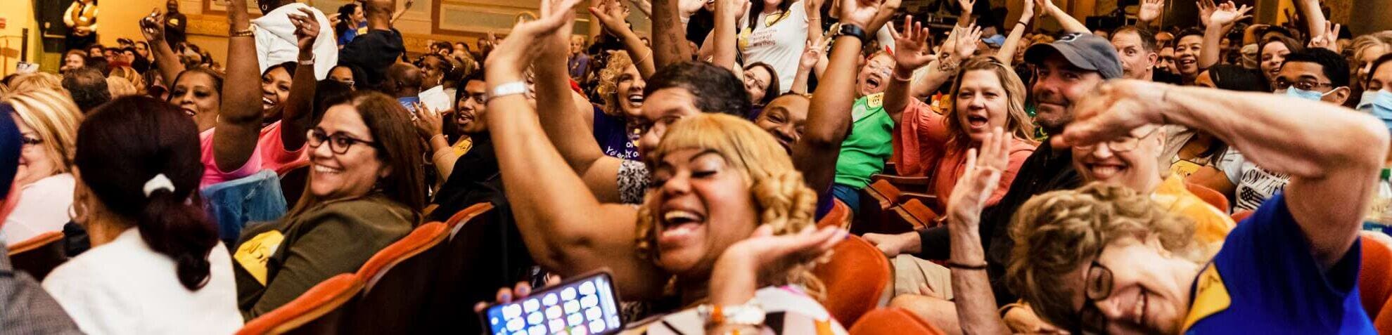 Guests attend The Price is Right in the Strand Theatre. They are smiling and waving.
