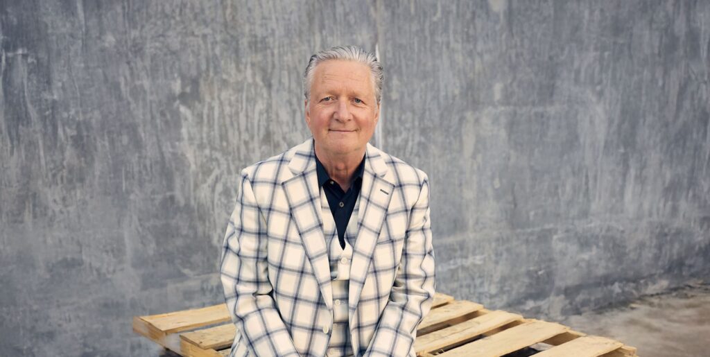 Glenn Tilbrook sitting on a shipping pallet in a patterned suit