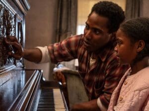 A scene from The Piano Lesson with an adult man and a young girl sitting at the piano